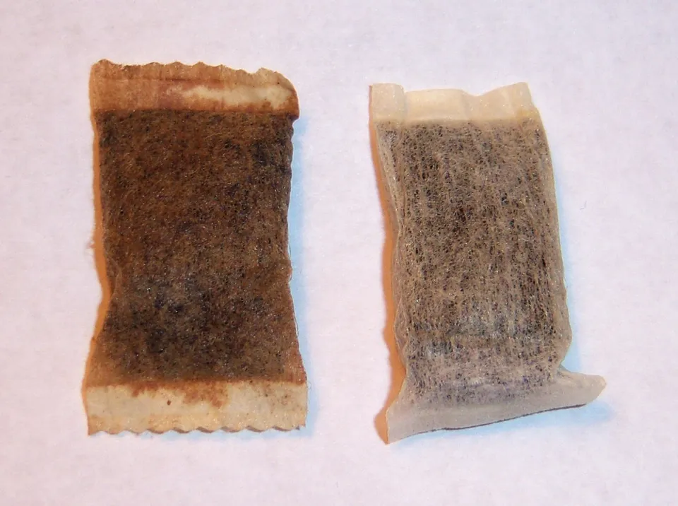 Original brown snus portion pouch next to a drier white portion pouch, side by side