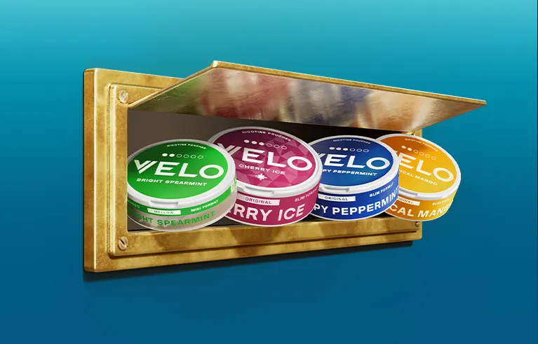 Official VELO banner showing four nicotine pouch cans on a gold display shelf with their dot gauges and format labels