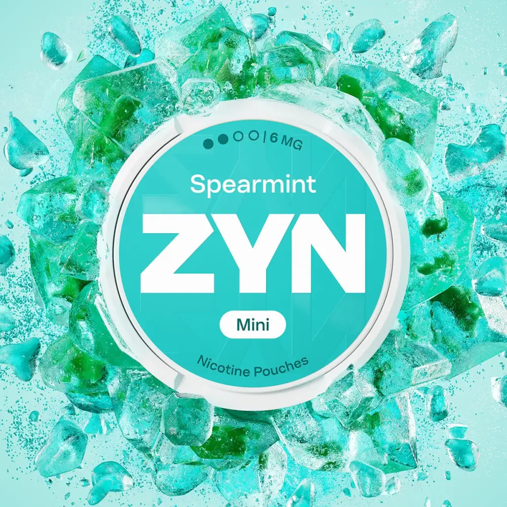 Official ZYN Spearmint nicotine pouches Mini 6mg can on a burst of green crushed ice